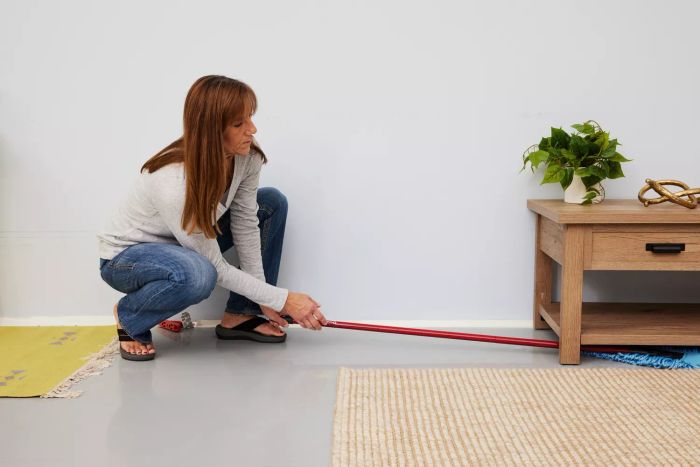 A person cleans beneath a table using the O-Cedar Dual-Action Microfiber Sweeper Dust Mop.