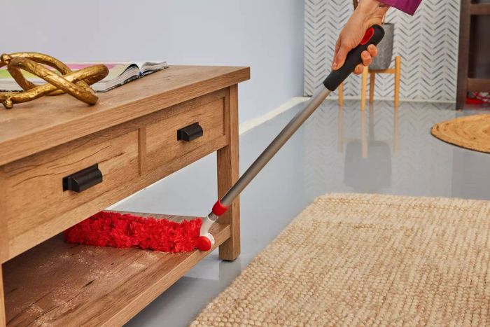 A person cleans using the OXO Good Grips Microfiber Extendable Duster.