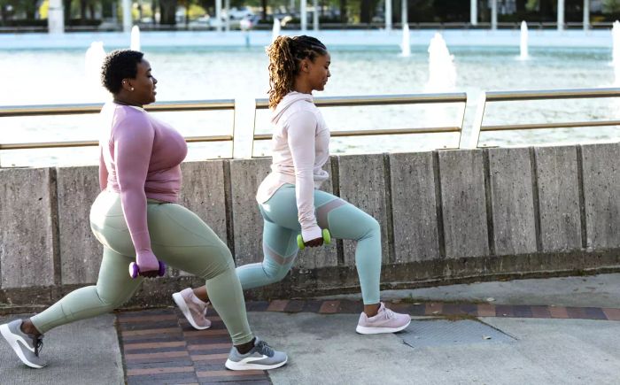 Full Body Workout: Two women performing lunges together in a park setting.