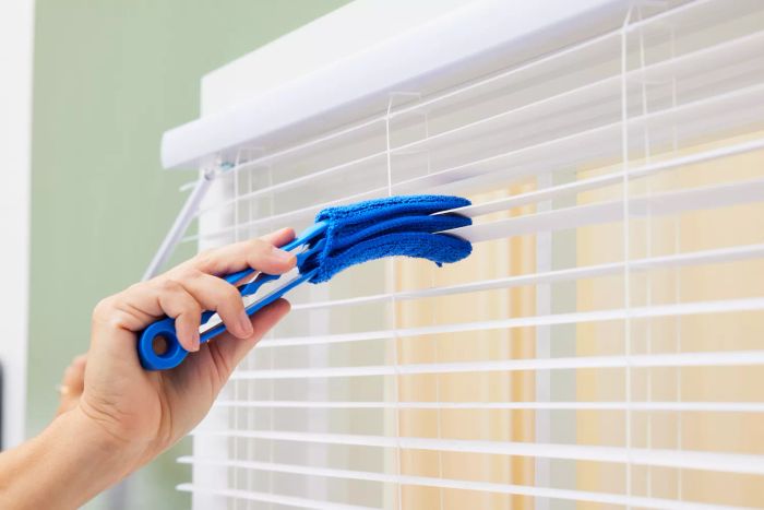 An individual uses the Hiware Window Blind Duster Brush to clean the blinds.