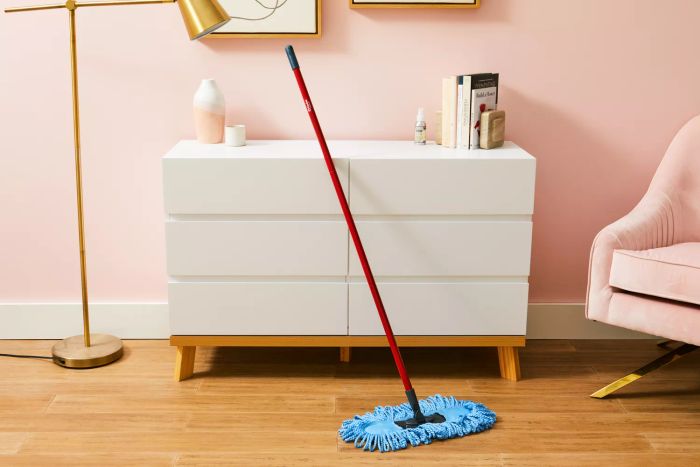 The O-Cedar Dual-Action Microfiber Sweeper Dust Mop rests against a dresser.